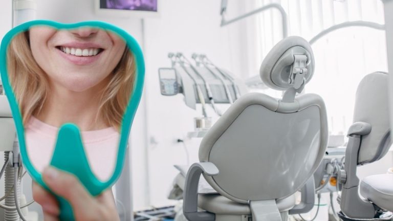 Smiling dental patient holding mirror after treatment at Cheer Dental clinic in San Jose